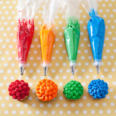 Nordic Ware pastry decorating set with four piping bags, colorful frosting tips, and four decorated cupcakes