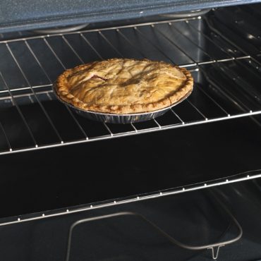 Oven liner mat on oven rack under baked pie
