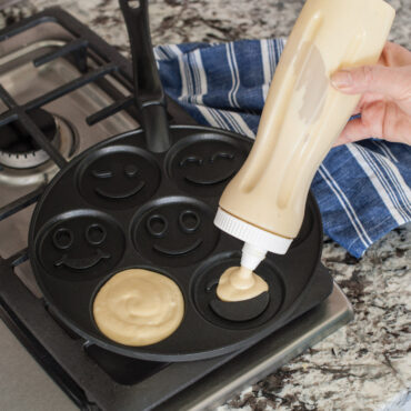 Pancake Dispenser filling cavities in a pancake pan on stovetop.