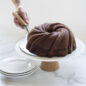 Baked Swirl Bundt on a cake stand with cake lifter lifting up