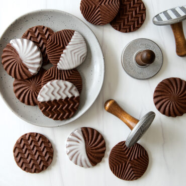 Plain and chocolate dipped geo stamped cookies on a plate and on surface, chocolate