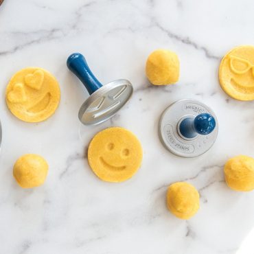Dough balls on surface, three stamped dough balls with emoji face design