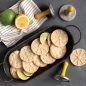 Baked citrus cookies in a tray with stamps and limes/lemons on surface