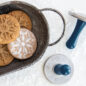 Closeup of stamped snowflake cookie stamps, in tray with stamps on surface