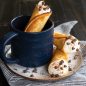 Filled krumkake with cream, chocolate chips and cocoa powder, one in mug and two on a plate