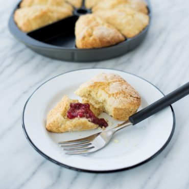 Baked scone wedge with berry jam on plate