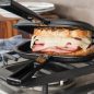 Grill press on stovetop with ham and cheese grilled sandwich
