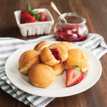 Nordic Ware cast aluminum ebelskiver pan with 7 round wells, filled golden spherical pancakes with jam