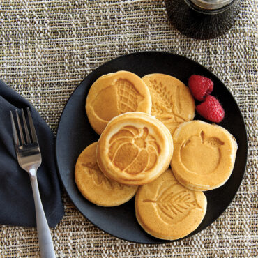 Cooked pancakes in cute autumn designs on a plate with maple syrup