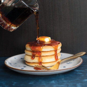 Golden maple syrup pouring onto stack of mini silver dollar pancakes from Nordic Ware pancake pan
