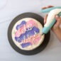 Hand decorating white frosted cake using Deco Pen