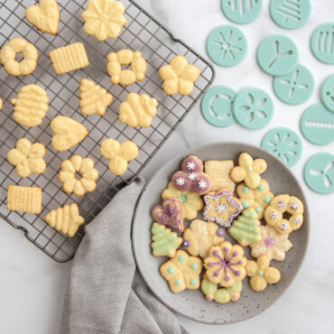Assorted decorated spritz cookies in star, flower, and spiral shapes with colorful icing and sprinkles