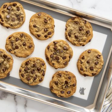 Baked chocolate chip cookies on Deluxe Silicone Baking Mat in a sheet pan.