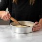 Person smoothing dough in a circle cake pan using angled spatula