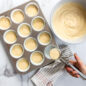 Pouring muffin batter into liners in muffin pan