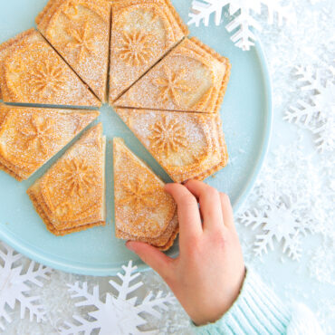 Baked shortbread, 8 diamond shape pieces with hand grabbing a piece