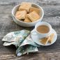 Baked shortbread squares in bowl, cup of tea