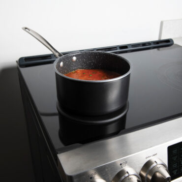 Lifestyle image of saucepan on heat tamer over an induction stove