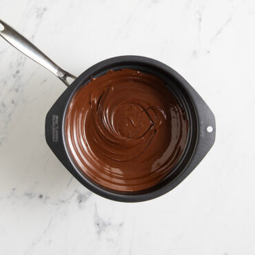 Overhead image of melted chocolate inside double boiler in sauce pan