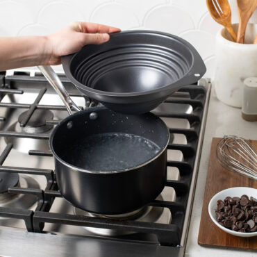 Hand holding double boiler over boiling water in a sauce pan.