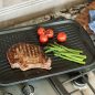 Flag griddle with steak, asparagus, tomatoes, on stovetop