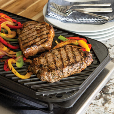 Grilled steak and colorful bell peppers on ridged side of Nordic Ware two-burner reversible griddle