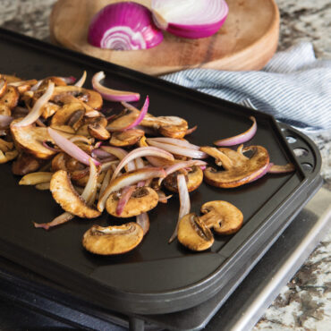 Sautéed sliced mushrooms and onions on Nordic Ware aluminum reversible griddle, flat side, on stovetop