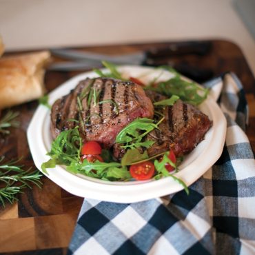 Grilled steak with greens and tomatoes on plate
