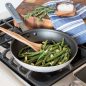 Cooked green beans in 10" skillet on stovetop, cutting board and bowl of salt on the side.