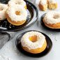 Baked vanilla donuts on plates with white glaze and white sprinkles