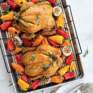 Two golden roasted whole chickens with vegetables on Nordic Ware Extra Large Oven Crisp aluminum baking tray