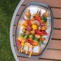 Grilled veggie and chicken kabobs on grill n' serve plate on outdoor table.