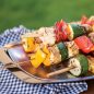 Closeup of kabobs on grill n' serve plate with towel