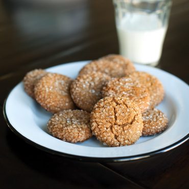 Ginger cookies on a plate with milk on the side.