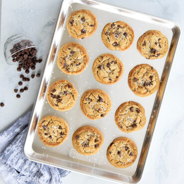 Golden chocolate chip cookies cooling on Nordic Ware aluminum half sheet pan with natural silver finish