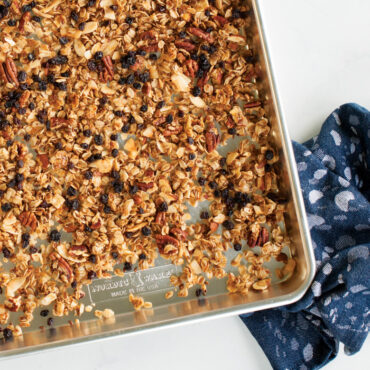 Nordic Ware aluminum half sheet pan with golden baked granola spread evenly across surface