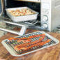 Casserole pan with food in toaster oven, sheet pan with bacon on rack