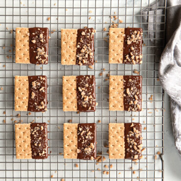 Chocolate-dipped shortbread cookies with chopped nuts cooling on Nordic Ware wire grid rack