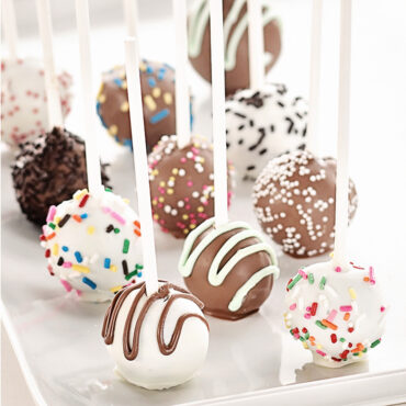 Colorful decorated cake pops on Nordic Ware paper sticks - pink, yellow, and white with sprinkles