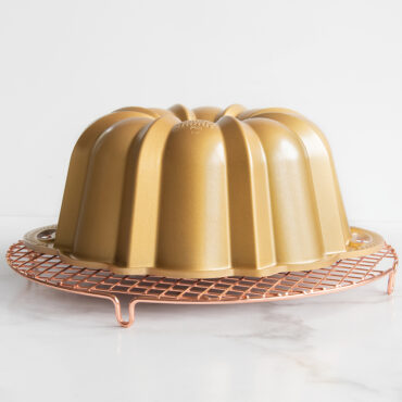 Angled shot of gold Anniversary Bundt pan inverted onto round cooling grid