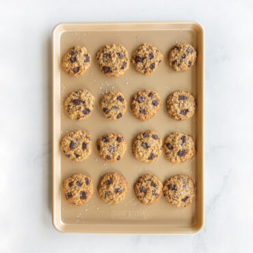 Sixteen golden chocolate chip cookies arranged in rows on Nordic Ware nonstick big sheet baking pan