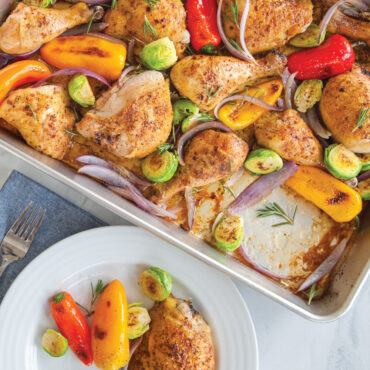Golden roasted chicken thighs with colorful bell peppers and Brussels sprouts in Nordic Ware aluminum sheet pan