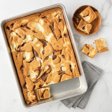 Golden brown chocolate chip blondies in Nordic Ware aluminum high-sided sheet cake pan, cut into squares