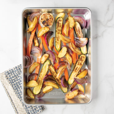 Colorful roasted vegetables in Nordic Ware aluminum high-sided sheet cake pan, golden and caramelized
