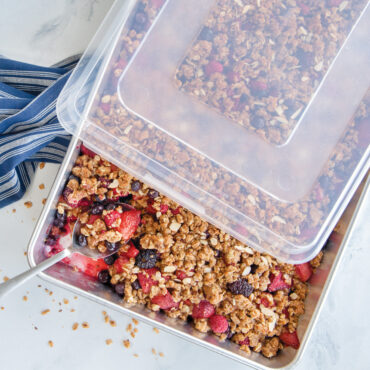 Nordic Ware aluminum high-sided sheet pan with clear lid containing baked berry crisp with golden crumbly topping