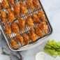 Baked barbeque chicken wings in bacon pan, celery stalks and ranch dressing