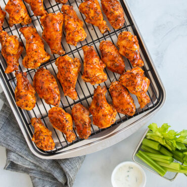 Golden-brown barbecue chicken wings on Nordic Ware aluminum oven crisp baking tray with celery and ranch