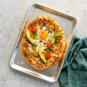 Nordic Ware aluminum quarter sheet pan with breakfast pizza topped with eggs, cheese, and vegetables
