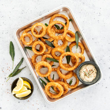 Nordic Ware aluminum quarter sheet pan with golden-brown breaded onion rings, natural silver finish