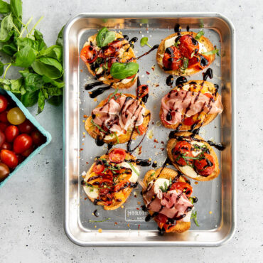 Nordic Ware aluminum quarter sheet pan with toasted bruschetta topped with diced tomatoes and herbs